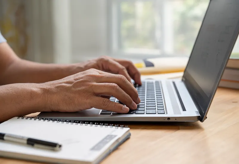 A close-up of hands typing on a laptop (AI-generated)