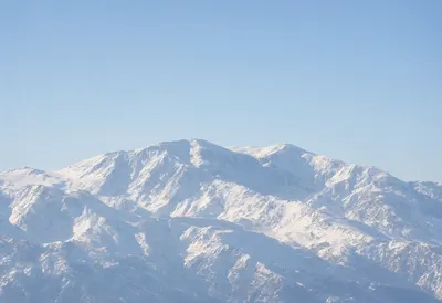 Vast Snow-Covered Mountain Range Under Blue Sky (AI-generated)