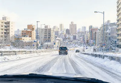 Snowy Urban Road with City Buildings in Winter (AI-generated)