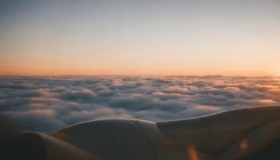 Airplane Wing Above Clouds at Sunset (AI-generated)