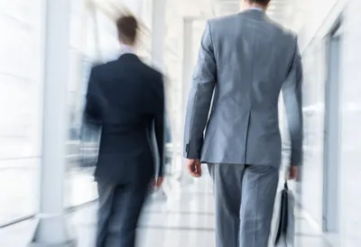Two Colleagues Walking through a Glass Corridor