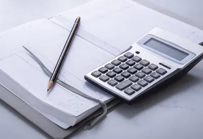 Calculator and Ledger on a Grey Desk