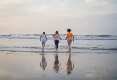 Children Running along a Beach at Dusk