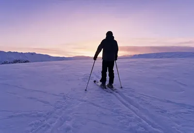 Skier Pausing on a Slope at Dusk