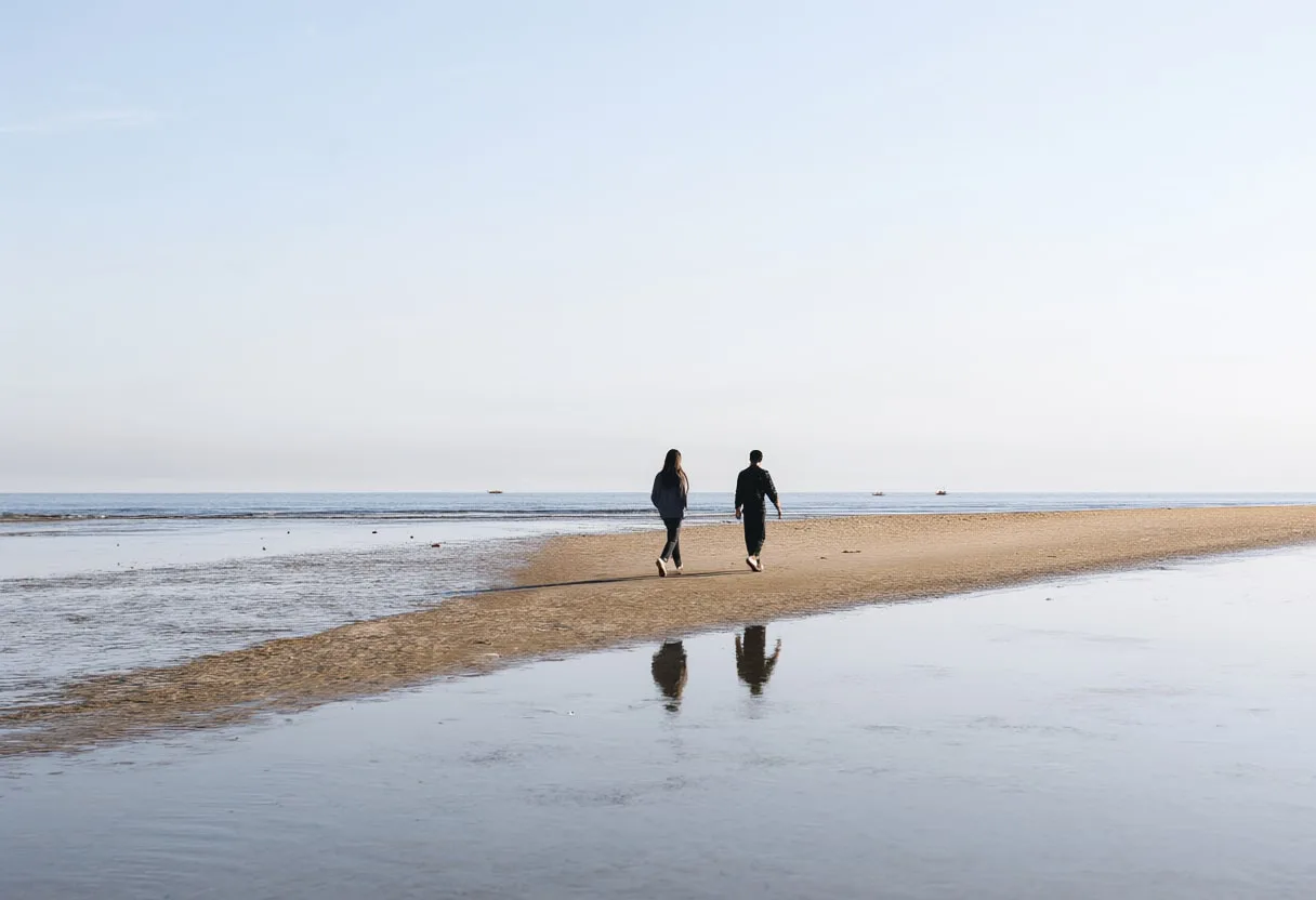 Two People Crossing a Sandbar at Low Tide