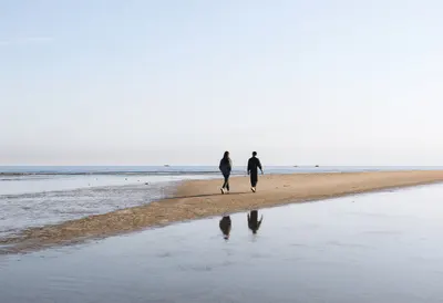 Two People Crossing a Sandbar at Low Tide