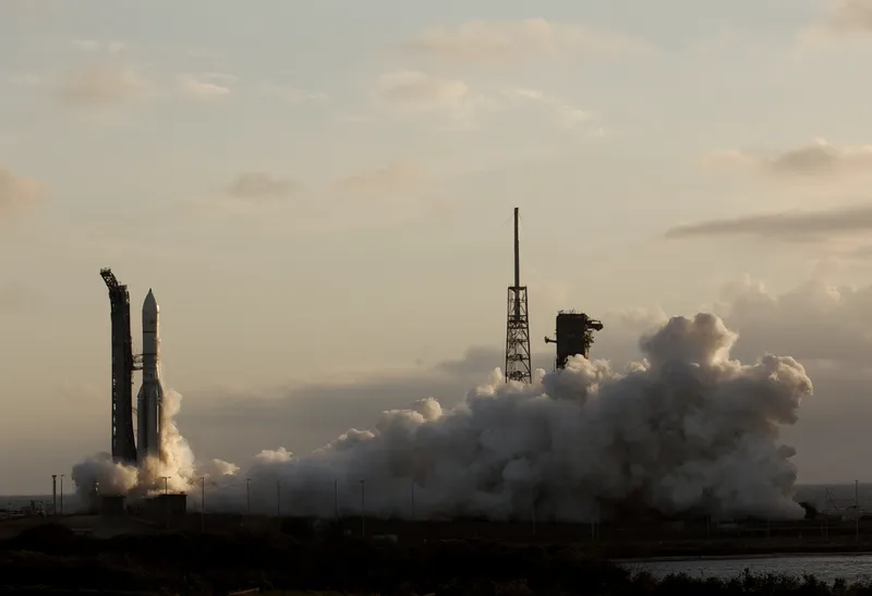 Rocket lifting off from a coastal launch pad at golden hour