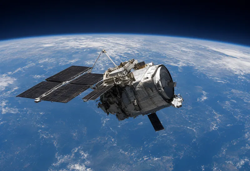 Communications satellite orbiting above Earth with solar panels deployed
