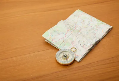 Folded Paper Map With A Brass Compass on a warm wooden table
