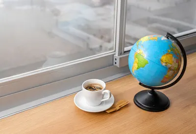 Globe And A Cup Of Coffee At A Window on a warm wooden table