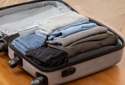 Open Suitcase With Neatly Folded Clothes on a warm wooden table