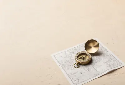 Folded Paper Map With A Brass Compass against a warm plaster wall Pencil Sketch
