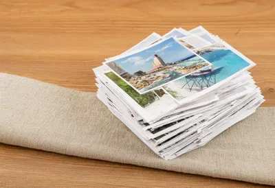 Stack Of Travel Postcards On Linen on a warm wooden table