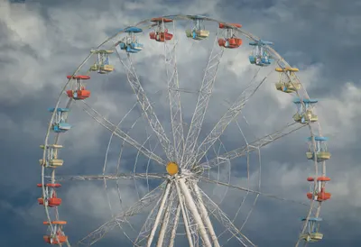 Ferris wheel with dramatic clouds, wide angle