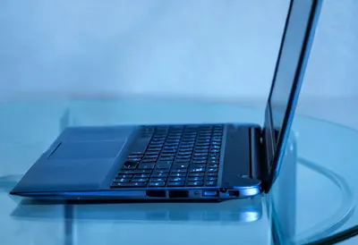 Laptop on glass desk with cool blue light, low angle